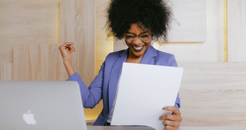 Dark haired woman smiling very intensely at a blank piece of paper