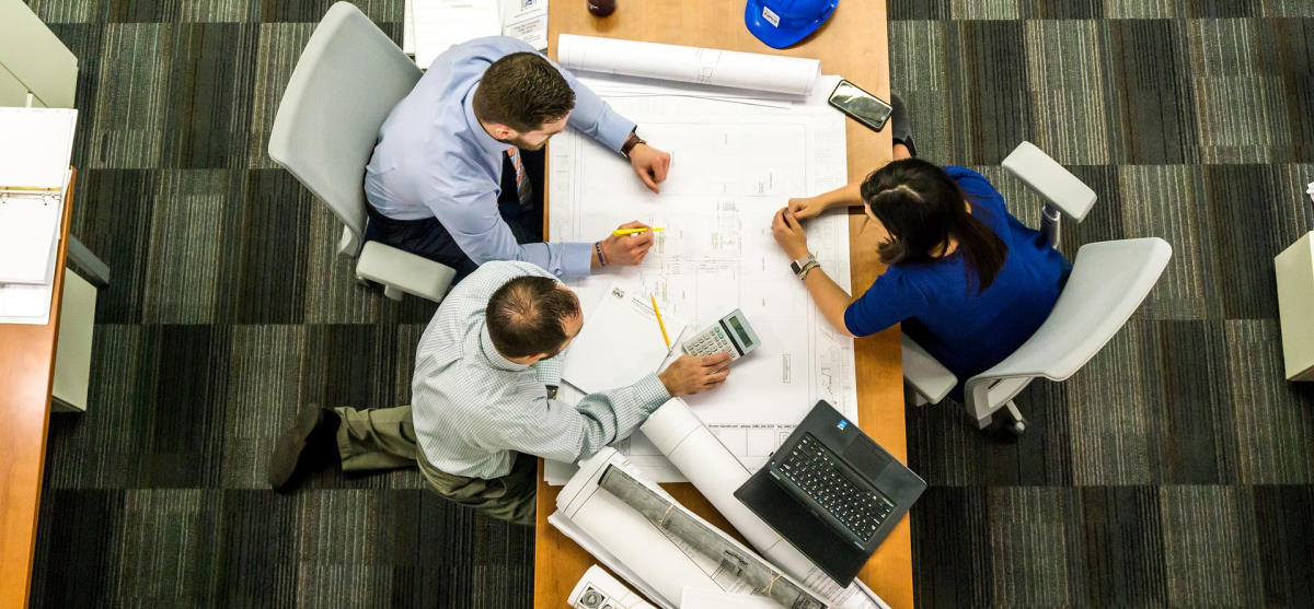 Overhead view of small group looking over drafting drawing